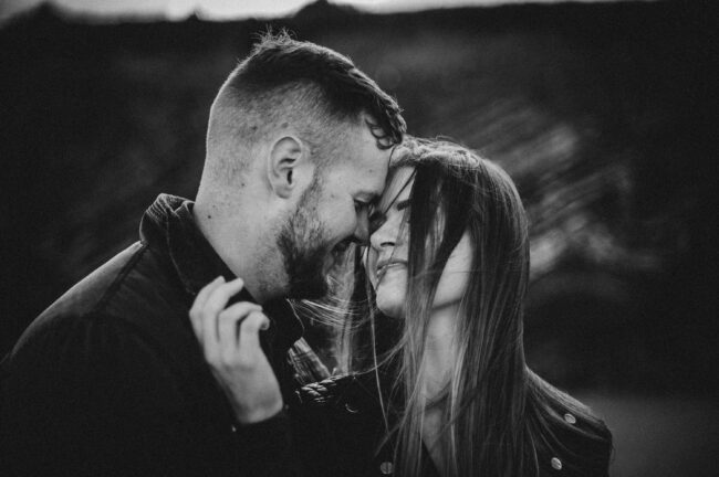 Paul and Ruth during their engagement session on a beach in Cork, Ireland, captured by a professional photographer, with stunning cliffs and ocean in the background.