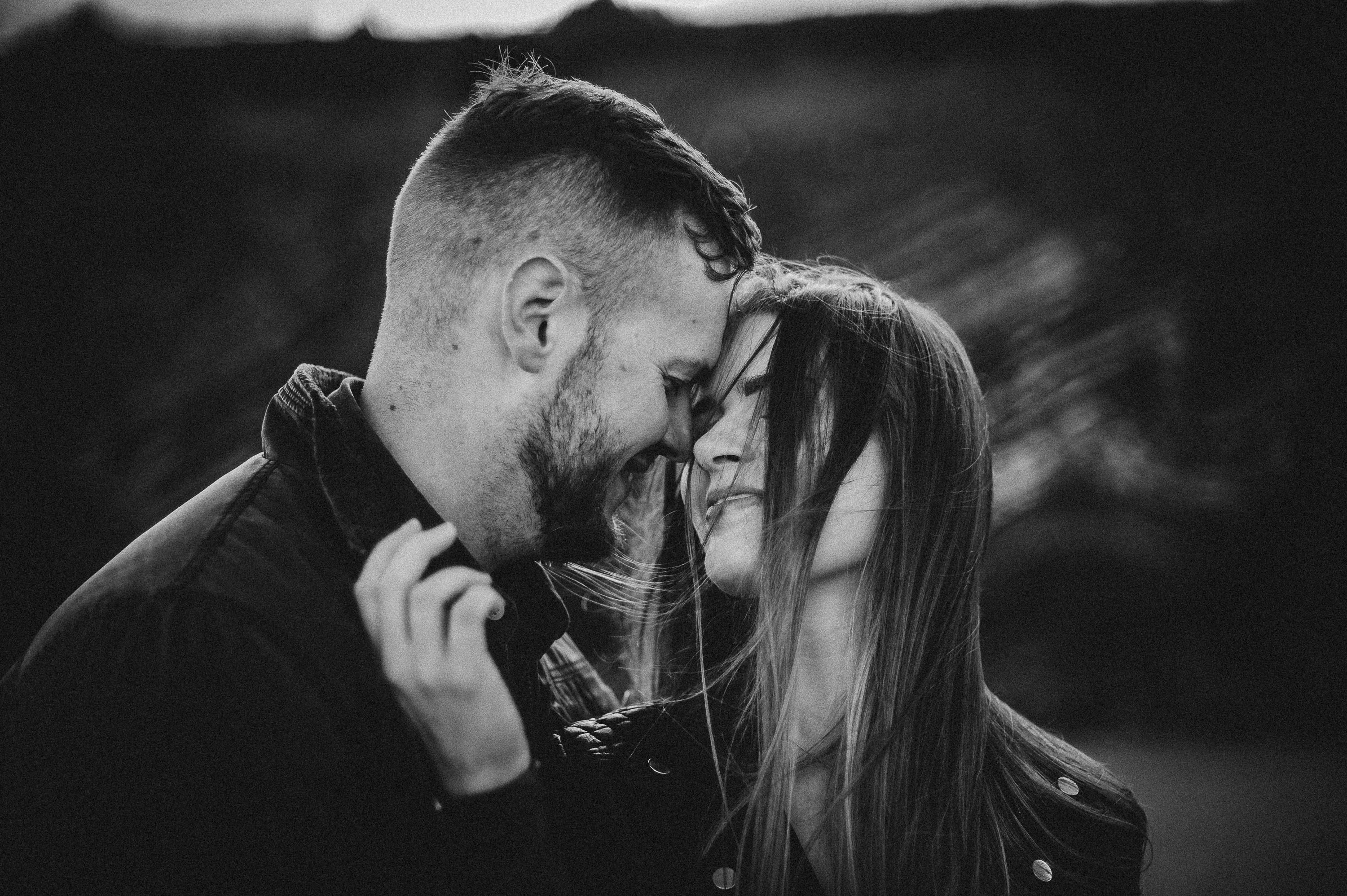 Paul and Ruth during their engagement session on a beach in Cork, Ireland, captured by a professional photographer, with stunning cliffs and ocean in the background.